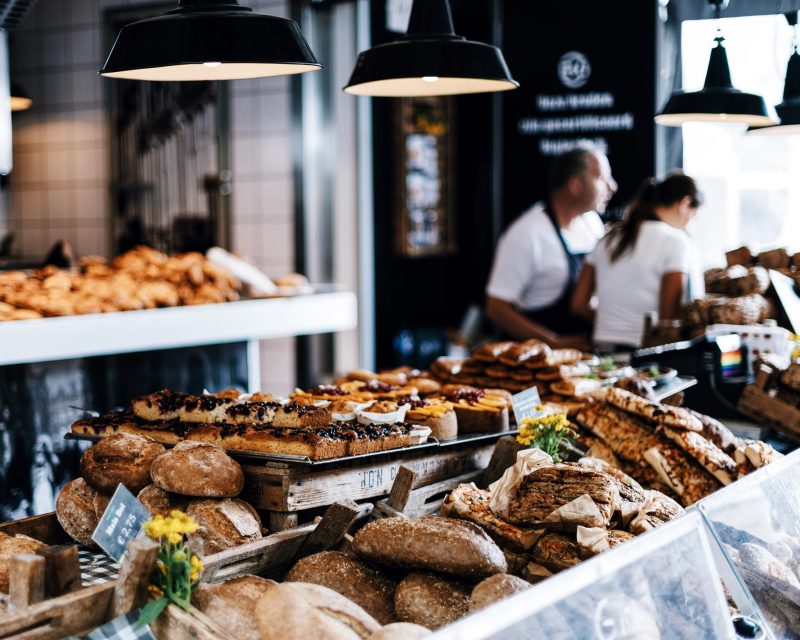 A vibrant display of freshly baked pastries, arranged on rustic wooden shelves in a warmly lit bakery.